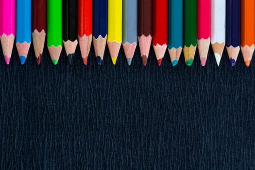 Black background for presentation with horizontal colourful upper border of multicoloured wooden pencils