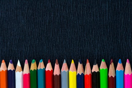 Black background for presentation with horizontal colourful bottom border of multicoloured wooden pencils