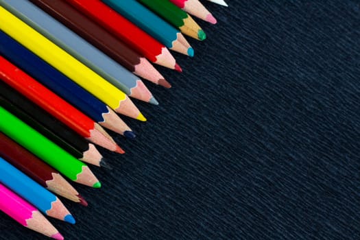 Black background for presentation with colourful right upper corner of multicoloured wooden pencils