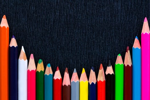Black background for presentation with round horizontal colourful bottom border of multicoloured wooden pencils