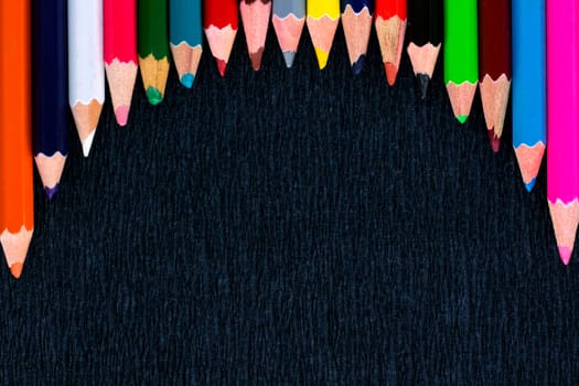Black background for presentation with round horizontal colourful upper border of multicoloured wooden pencils