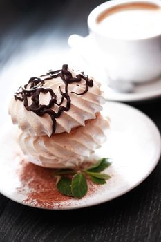 Cake on plate near cup of coffee on dark wooden table