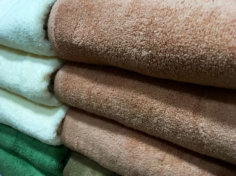 Closeup of colorful towels on the shelf. Stack of rolled towels