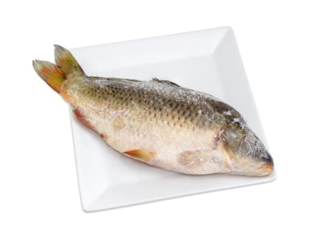 Frozen carp prepared for cooking on a white square dish on a light background
