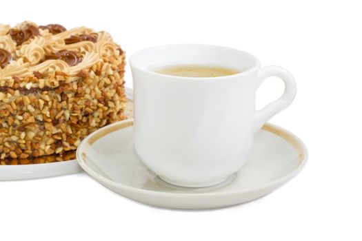 White cup with coffee with cream on a background of sponge cake, decorated with butter cream and sprinkled with grated nuts on a light background
