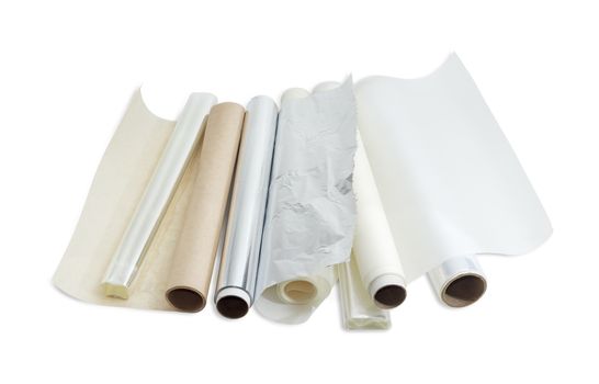 Several rolls of the plastic oven bags, plastic food wrap, aluminum foil and various parchment paper for household use on a light background. 
