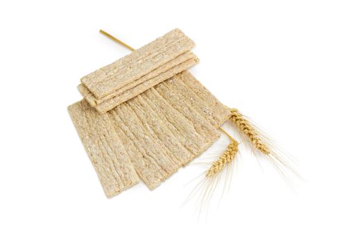 Dietary wheat wholegrain crispbread with adding buckwheat and barley and two wheat spikes on a light background
