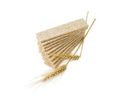 Pile of the dietary wheat wholegrain crispbread with adding the buckwheat and the barley and two wheat spikes on a light background
