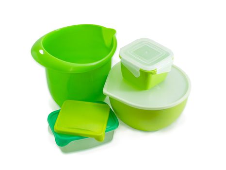 Several different green reusable plastic food storage and cooking containers, some with covers, for home use on a light background
