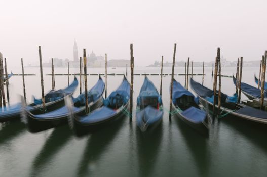 Gondolas, the traditional flat-bottomed Venetian rowing boats, at their moorings in San Marco Square at sunrise, with the lagoon and the church of San Giorgio Maggiore in the background, Venice, Veneto, Italy, Europe (intentional motion blur)
