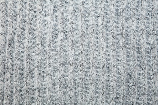 Close up on knit woolen fur texture. Gray melange fluffy woven thread sweater or scarf as a background.