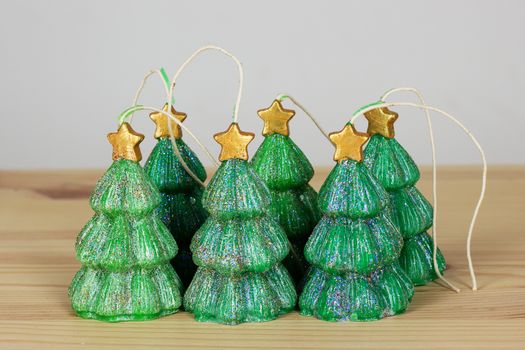 Green handmade Souvenir candles in the shape of Christmas trees on a wooden textural background