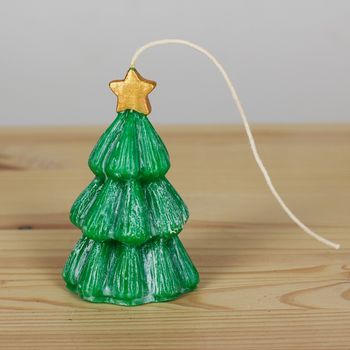 Green handmade Souvenir candles in the shape of Christmas trees on a wooden textural background