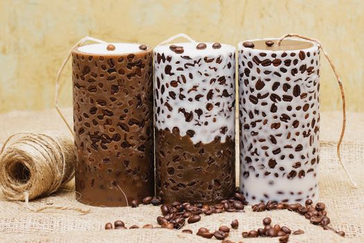 Beautiful Decorative Handmade candle with coffee beans on old sackcloth background. Candlelight.