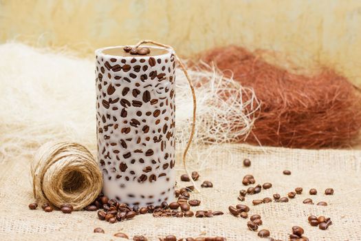 Beautiful Decorative Handmade candle with coffee beans on old sackcloth background. Candlelight.