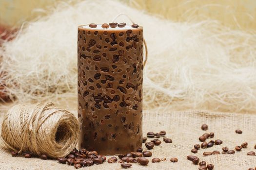 Beautiful Decorative Handmade candle with coffee beans on old sackcloth background. Candlelight.