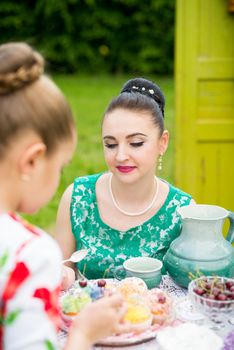 mother with daughter have a breakfast in the garden