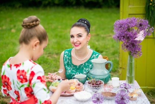 mother with daughter have a breakfast in the garden