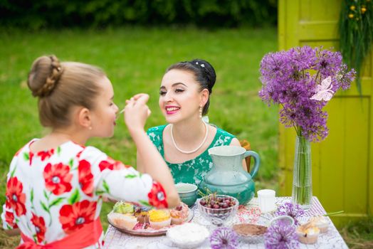 mother with daughter have a breakfast in the garden