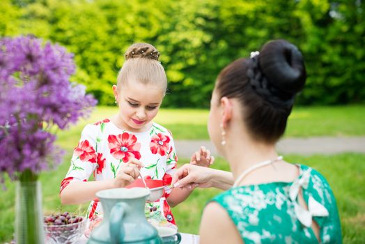 mother with daughter have a breakfast in the garden