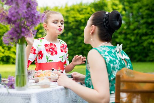 mother with daughter have a breakfast in the garden