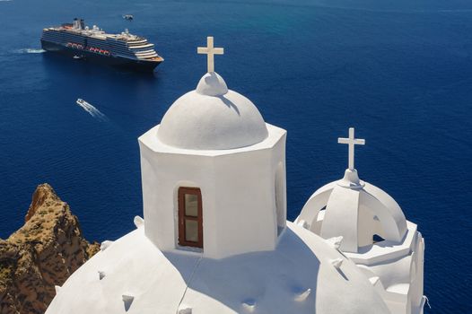 White orthodox church bell tower and sea with ships at background. Fira, Santorini Greece. Copyspace