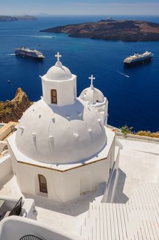 White orthodox church bell tower and sea with ships at background. Fira, Santorini Greece. Copyspace