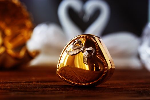 Closeup gold gift box of heart on old wooden table. gold heart-shaped box .Valentine's Day concept.