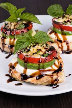 Chicken breast with slices of mozzarella, avocado, tomato and basil
