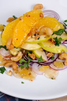 Salad with slices of orange, apple, blue onion, raisin, nuts, cashew nuts, herbs and honey sauce