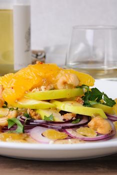 Salad with slices of orange, apple, blue onion, raisin, nuts, cashew nuts, herbs and honey sauce