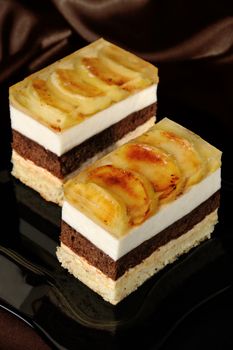 Cake stacked from caramel, apple mousse, chocolate and almond biscuit with a jelly layer of slices caramelized apple