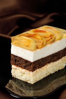 Cake stacked from caramel, apple mousse, chocolate and almond biscuit with a jelly layer of slices caramelized apple