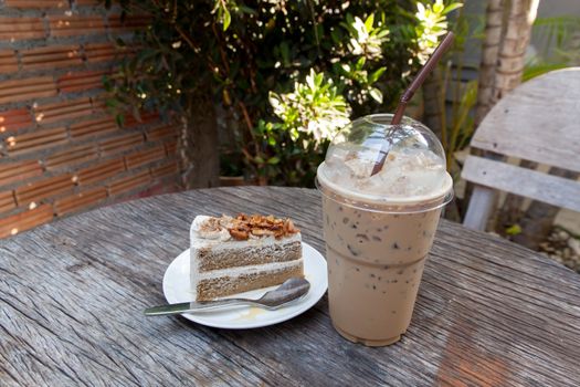 Coffee cake with topping almond on white plate  and hot espresso on old wood table