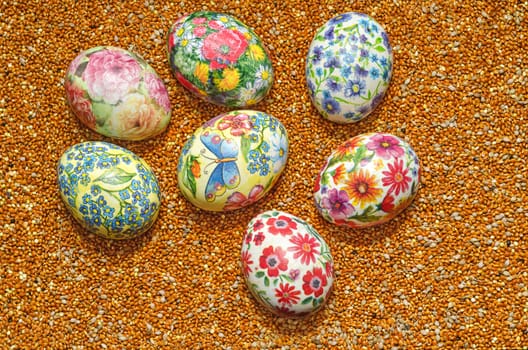Decoupage Easter eggs are handmade, but on the background of scattered millet.