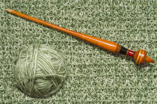 The ball of yarn on a background of knitted fabrics and old spindle.