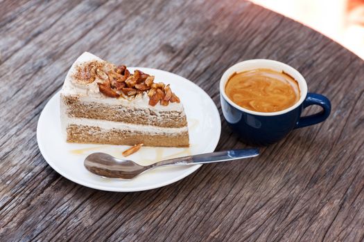Coffee cake with topping almond on white plate  and hot espresso on old wood table
