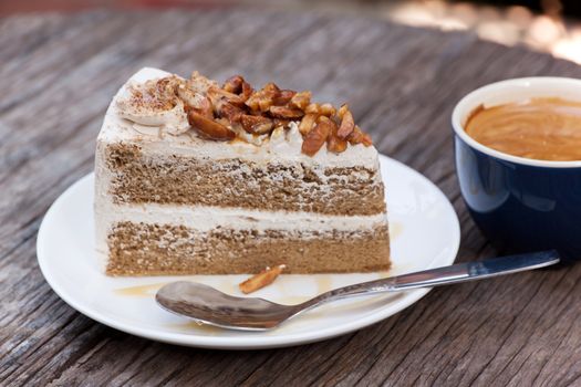 Coffee cake with topping almond on white plate  and hot espresso on old wood table