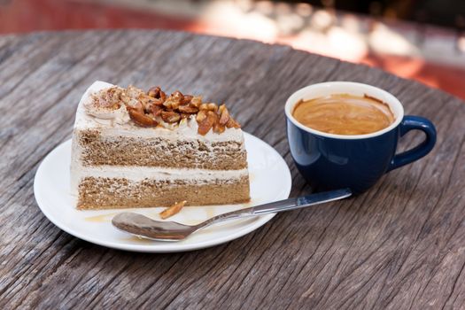 Coffee cake with topping almond on white plate  and hot espresso on old wood table