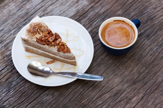 Coffee cake with topping almond on white plate  and hot espresso on old wood table