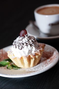 Cake on plate near cup of coffee on dark wooden table