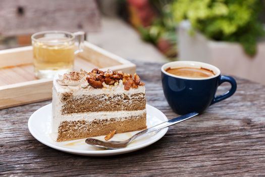 Coffee cake with topping almond on white plate  and hot espresso on old wood table