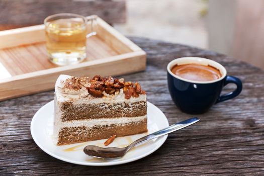 Coffee cake with topping almond on white plate  and hot espresso on old wood table