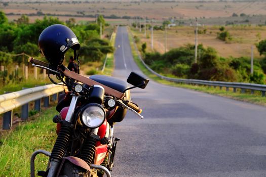 Tourist stop motorbike at roadside to relax after long trip, helmet on motorcycle, straight road at Vietnam countryside at evening, people on the way to adventure trip in Bau Trang, Binh Thuan