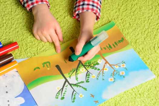 the child draws a picture lying on a green carpet