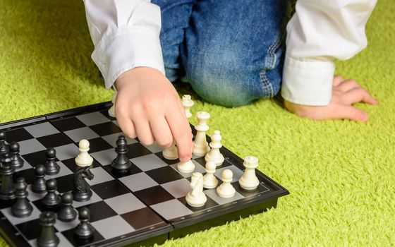 child playing chess sitting on the carpet