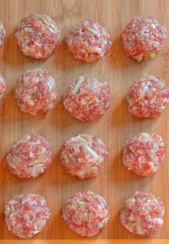 Raw Uncooked Meatballs on wooden plate