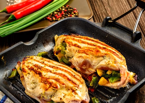 Juicy chicken fillet on a frying pan grill on a brown wooden background. Close up