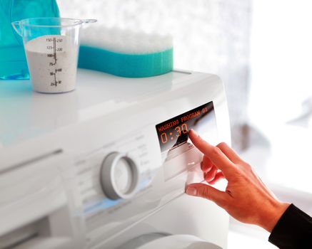 Close up of woman hand choosing program for washing machine