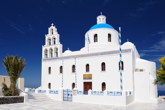 Oia, Santorini island, Cyclades, Greece - April 23, 2016: View to Orthodox church of Panagia with bell tower at central square. Oia is a small town and former community in the South Aegean on the islands of Thira AKA Santorini and Therasia, in the Cyclades, Greece.